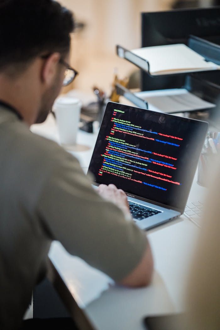 Home Focused programmer coding on a laptop in an office environment.